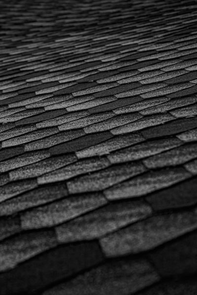Close-up of black roof shingles forming an abstract textured pattern, emphasizing geometry and modern architecture.